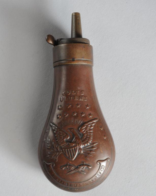 Small Colts Priming Flask: Colts Patent priming flask with thirteen stars above left facing eagle grasping shield and arrows above crossed firearms with "E Pluribus Unum" on banner below, (on one side only,) approx. 4 5/8" L. P
