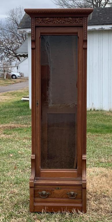 Early to Mid 20th C. American Carved Gun Cabinet: Molded edge cornice over decorative floral carving, glass door opening to space for 7 guns, single bottom drawer with brass pulls, some scratches and wear from use.H: approx. 72".W: approx. 24".D: app