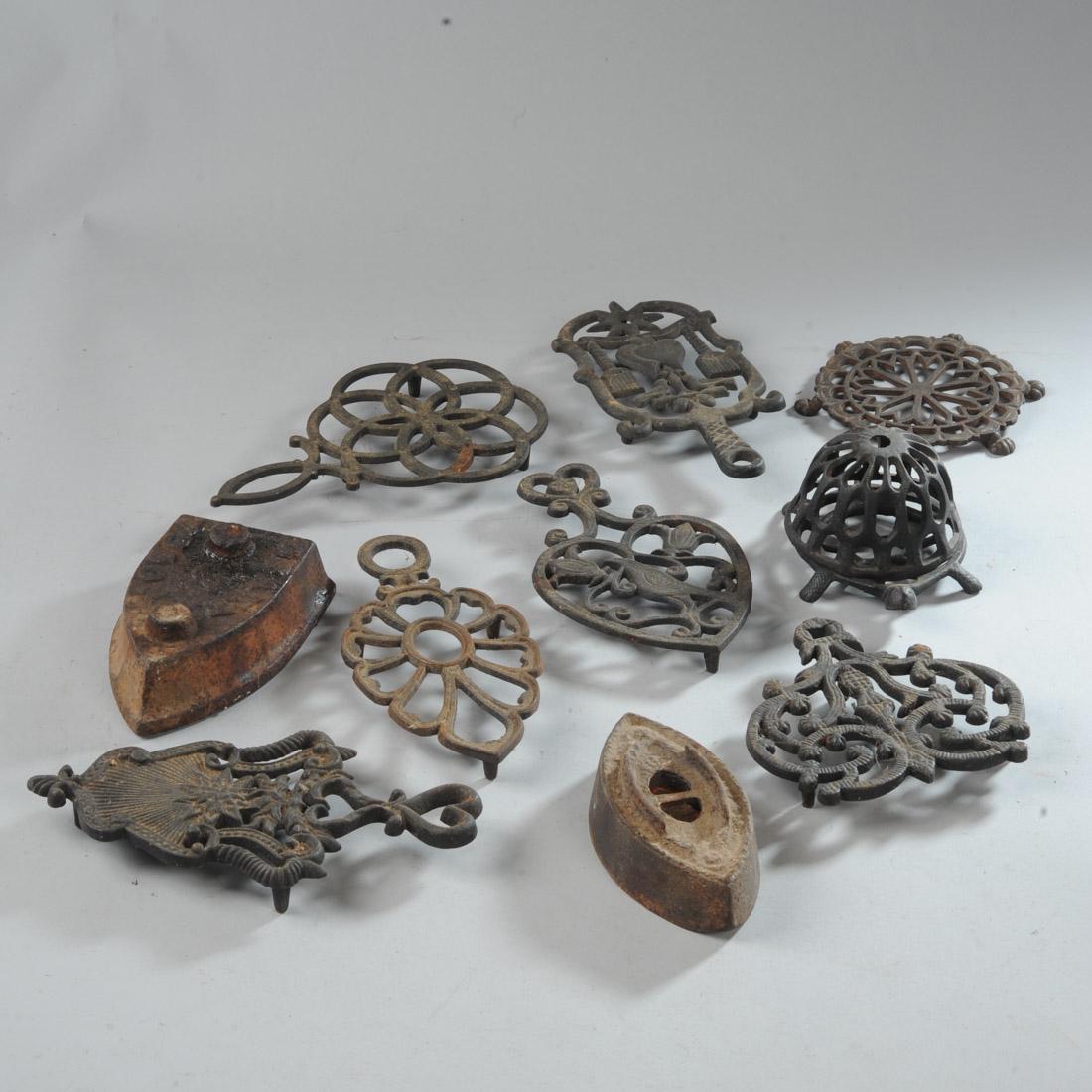 Antique Cast Iron Lot: To include seven iron trivets in various designs, a turtle-form iron string holder, and two sad irons, both missing handles, one marked: Chattanooga.