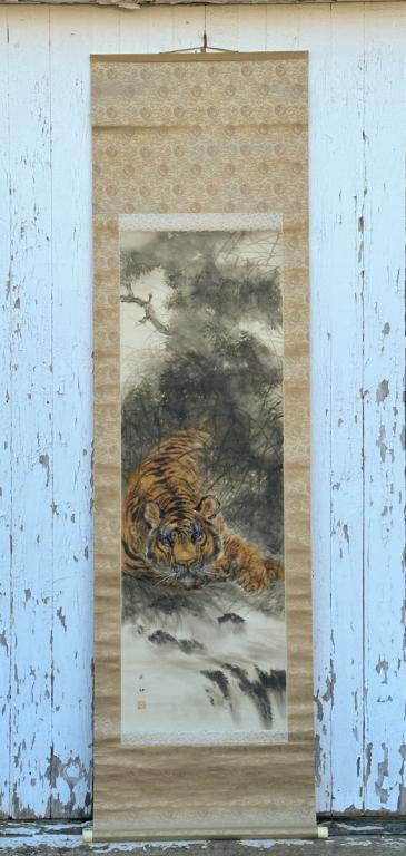 Japanese Scroll Painting of a Malayan Tiger: Ink and pigments on silk depicting a Malayan Tiger reclining in tall grass. With signature and red seal mark. Bone roller ends. Scroll, approx. 79" x 22 1/4". Image area approx. 51" x 17".