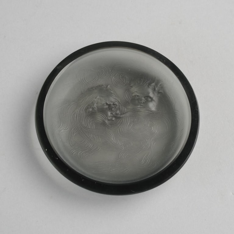 Rene Lalique Deux Zephyrs Cendrier: c1913 Rene Lalique ashtray or pin dish in topaz, showing two figures of the wind, their opposing currents swirling like smoke. Base with raised mark R. Lalique, and etched mark R. Lalique France. Appr