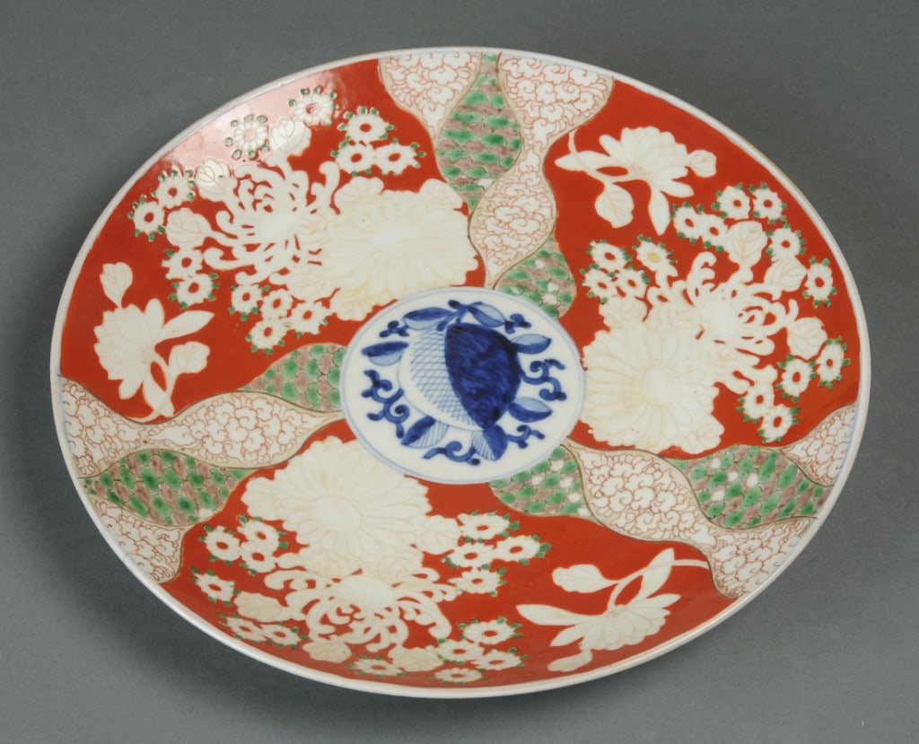 Antique Imari Charger: 19th C. Imari charger, the center with a peach and leaves in underglaze blue, surrounded by alternating panels of flowers and twisting brocade. Base with single kiln spur and with Fuku mark in undergl