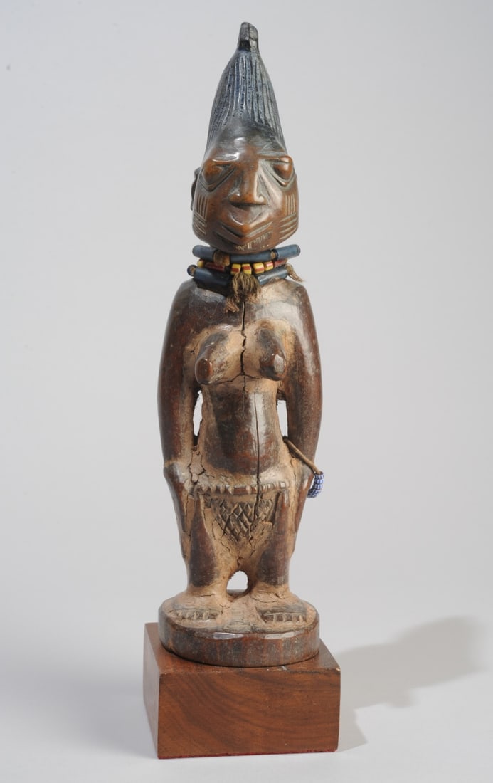 Yoruba 'Ere Ibeji' Female Twin Figure, Nigeria: With towering coiffure, bulging eyes, wide scarified cheeks, prominent breasts, arms at sides and pressed against hips. With label for James Willis Gallery, San Francisco. Age cracks. Embellished with