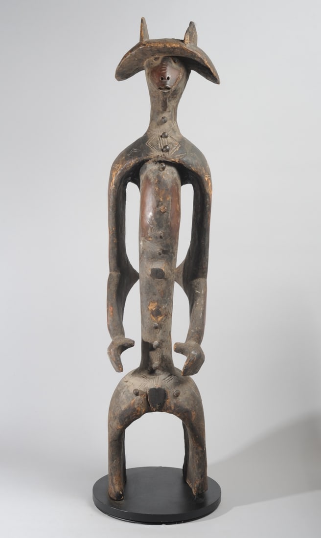 Mumuye Male Iagalagana Figure, Nigeria: Standing male guardian figure with particularly dynamic form, the face under the wide-brimmed headdress (or coiffure) expressing intense alertness. The posture, with shoulders back, elbows slightly be