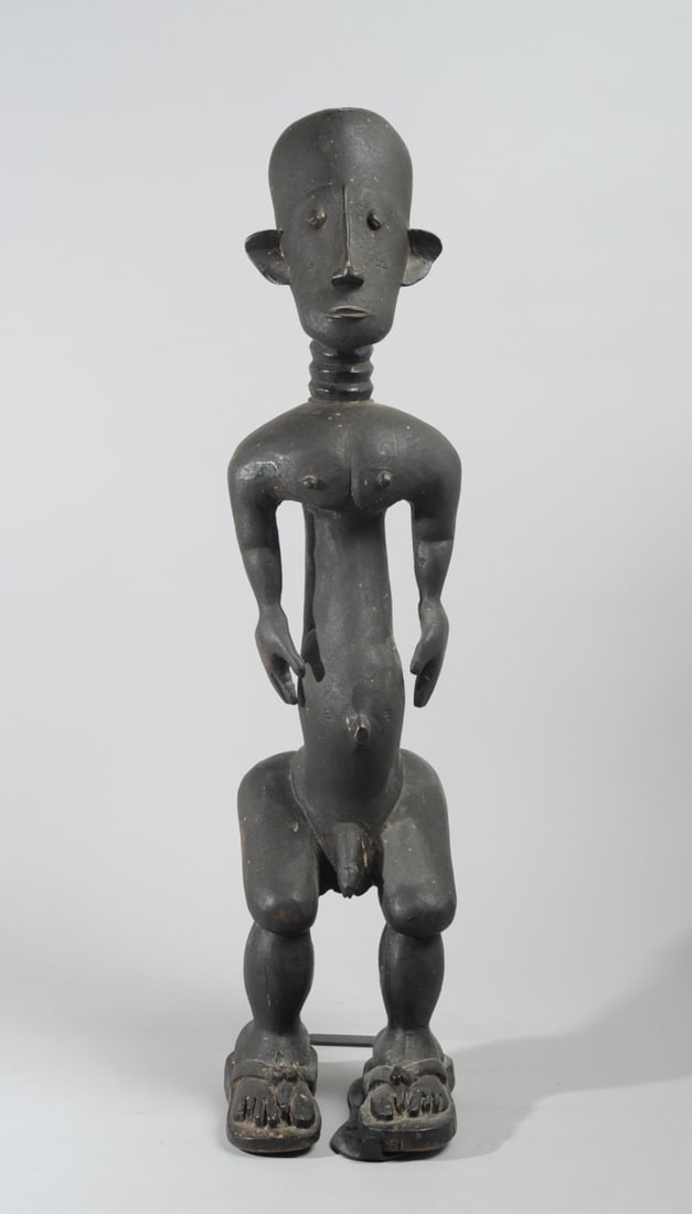 Ashanti Male Seated Figure: Likely a companion piece for lot 131. Seated male figure with long, ringed neck, muscular body with truncated arms. His wears only the sandals on his feet. Though seated, he is not provided with a sto