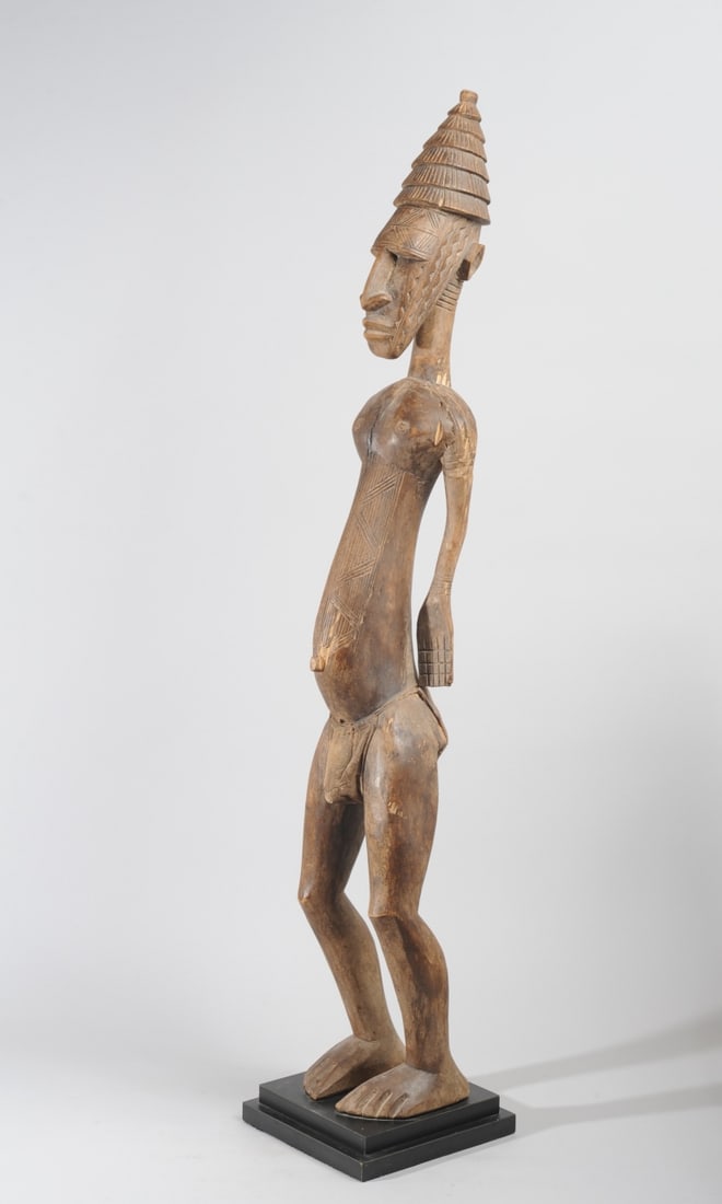 Bamana / Bambara Male Figure, Mali: Standing male figure with pointed, tiered headdress, the narrow face with heavy brow and long, straight nose, full lips, the muscular chest above narrow torso with protruding belly, the truncated arms
