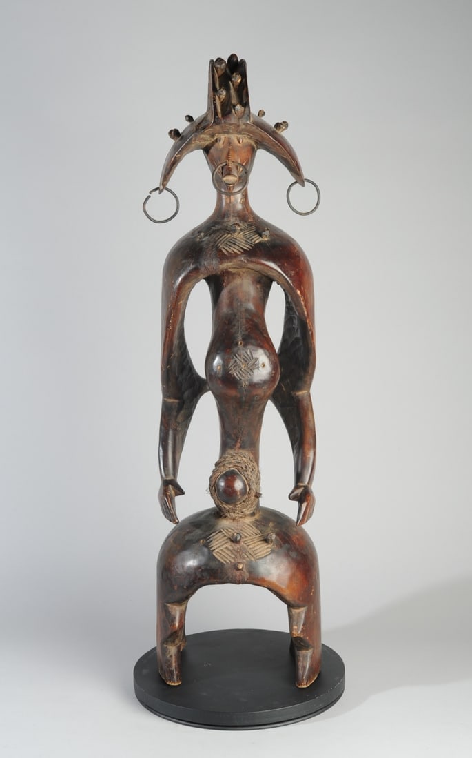 Mumuye Iagalagana Figure, Nigeria: Standing guardian figure with particularly dynamic form, the face under the wide-brimmed headdress (or coiffure) expressing intense alertness. The posture, with shoulders back, elbows slightly bent, c