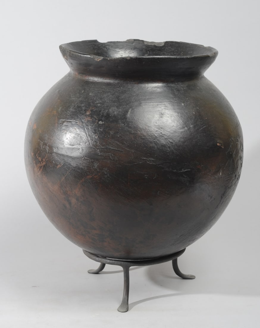 Lobi Black Pottery Vessel: Round pot with wide mouth, flared rim. On black wrought iron stand. Approx. 17" H, 14" D. Provenance: The Collection of Dr. Juris & Ingrida Simanis, Lexington, Virginia. Ex Thomas McNemar, Lexington,