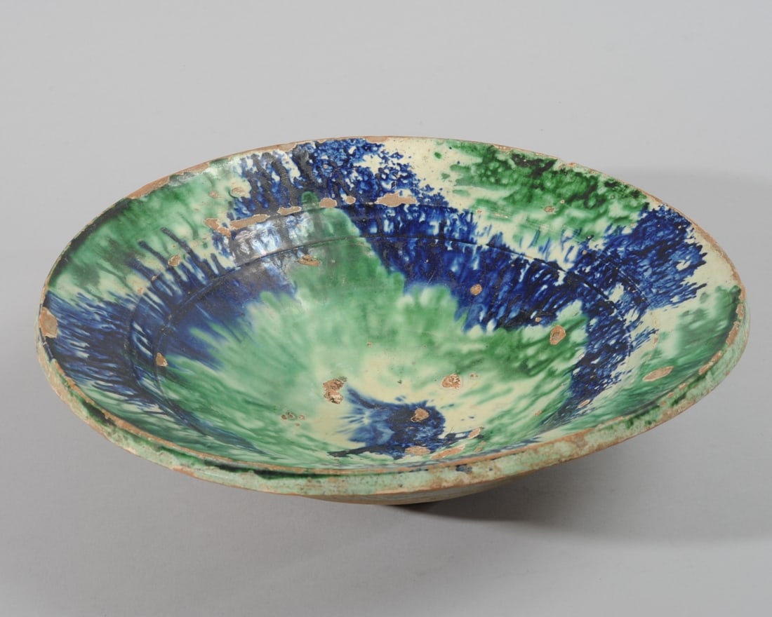 Mid East / Afghan Pottery Bowl: Heavily potted vintage or older redware bowl with splashes of green and dark blue glaze over creamy white to interior, exterior with transparent green glaze over red clay to upper half, lower half ung