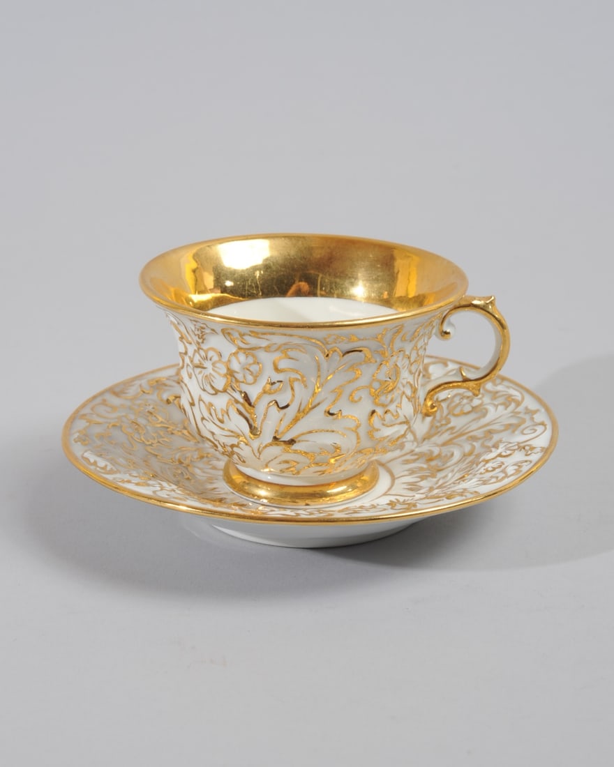 Meissen Relief Gold Teacup & Saucer: With relief scrolling acanthus and floral on white. Underglaze blue crossed swords mark on both pieces, appears to be as used 1815-1924. Saucer with model number A152. No chips, cracks, hairlines, rep