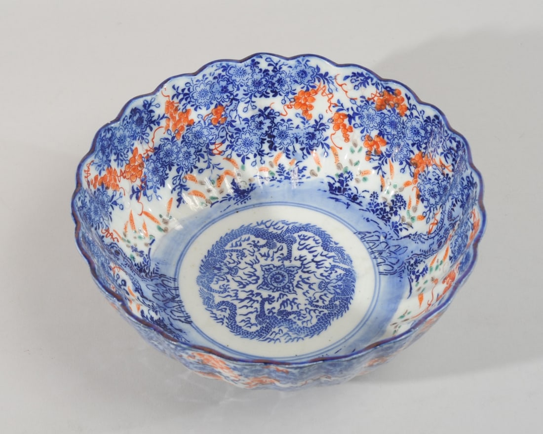 Japanese Meiji Arita Dragon Bowl: The center with a pair of confronting five-toed dragons and a flaming pearl. The sides with flowering blue trees and red grape vines, with touches of green and grey enamels. Scalloped rim. Unmarked. N