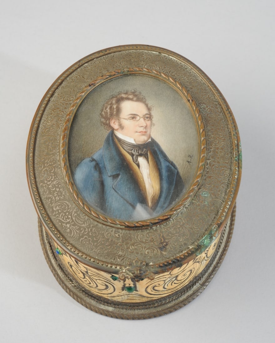 Franz Schubert Portrait Miniature Box: Oval bone box carved with neo gothic grotesques with glass gem eyes, the hinged lid a very fine ormolu mounted portrait miniature of Franz Schubert, signed A. R. Ormolu base, black velvet lining. Four