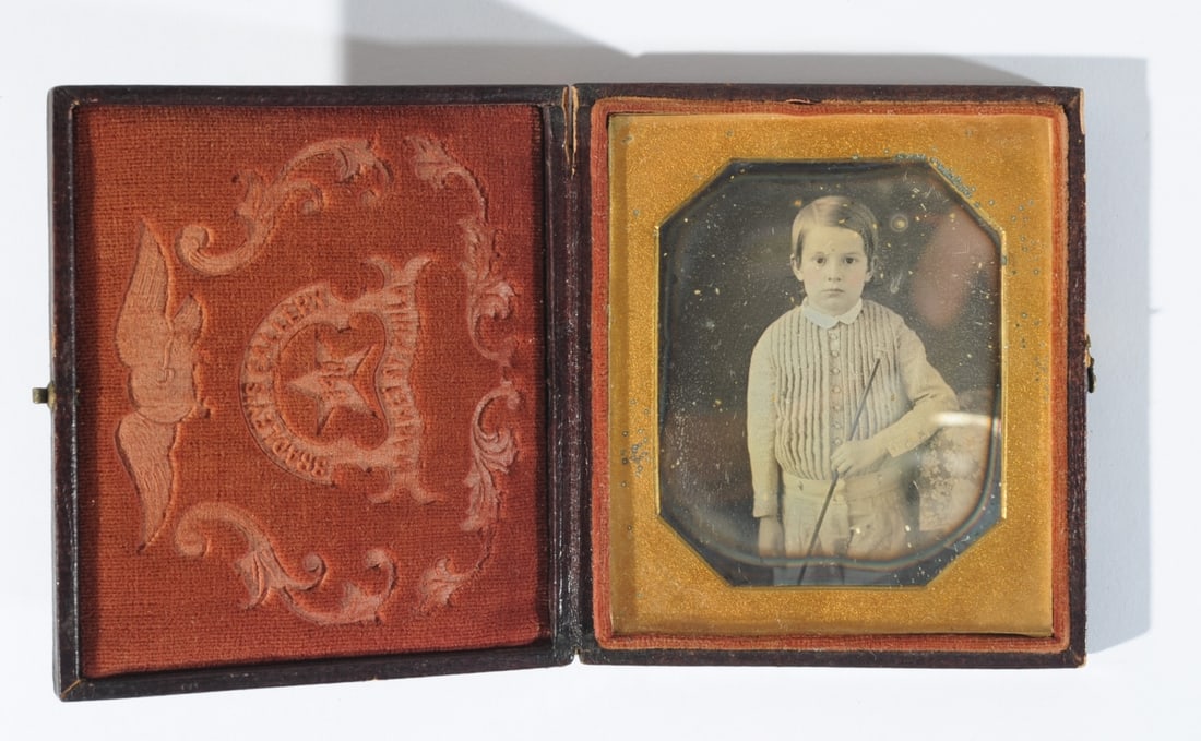 1/6 Plate Daguerreotype of Young Boy: Young boy with pink cheeks and serious face holding a baton. Red velvet lining of case with embossed eagle and "Bradley's Gallery, 340 Market St. Phila." Surface losses to case at corners. Case approx