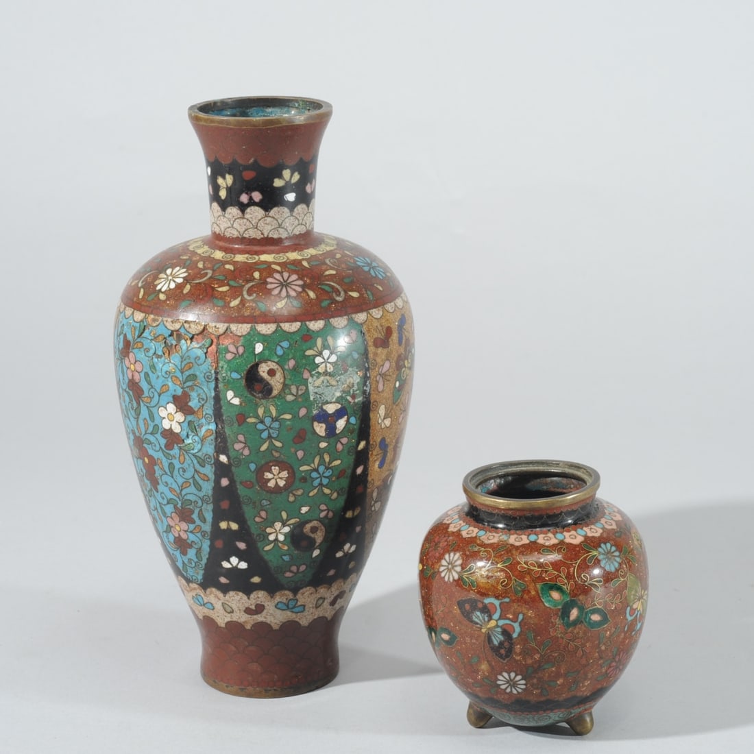 Two Japanese Goldstone Cloisonne Vases: Meiji or Taisho era 'goldstone' cloisonne vases, the larger with panels of flowers and butterflies, the smaller with a phoenix among flowers and butterflies. Both have a dent with minor surface losses