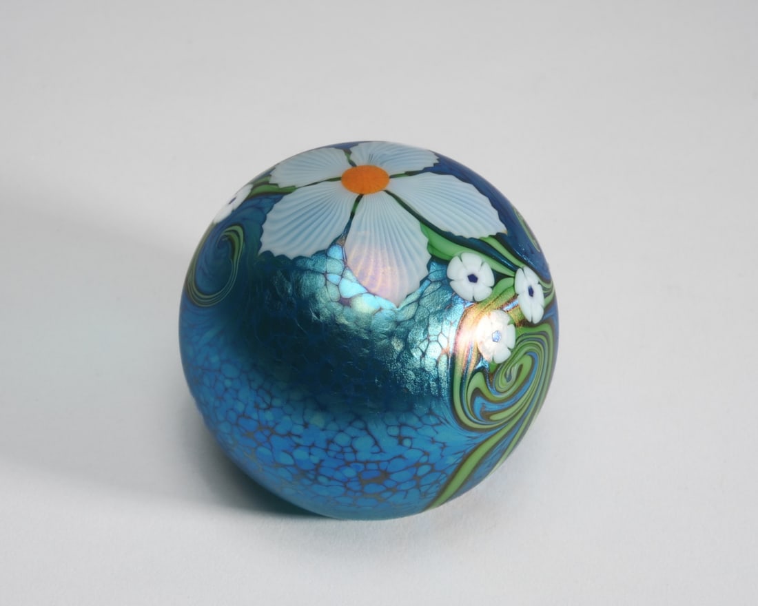 Orient & Flume Richard Braley Paperweight: Art glass paperweight with white flowers on an iridescent turqoise blue oil spot ground. Etched signature Braley to base with Orient & Flume and numerical marks. Approx. 3 1/2" H.