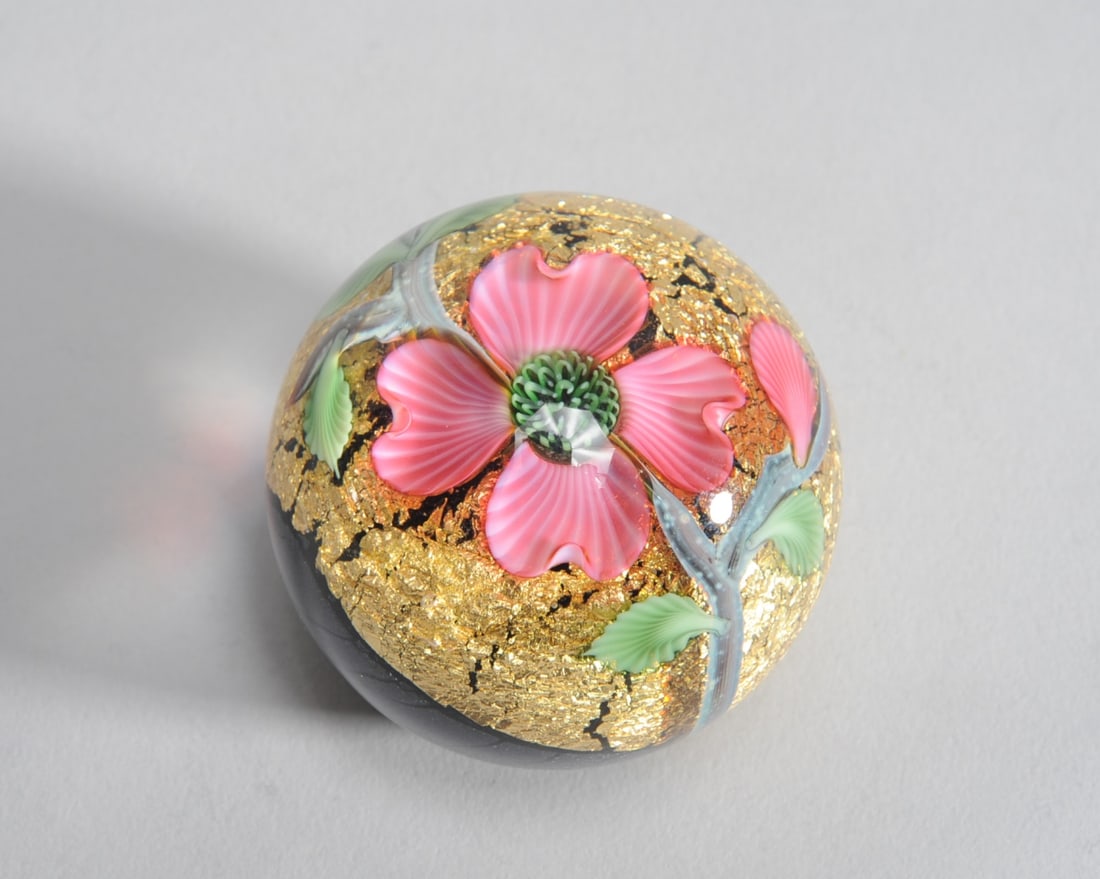 Orient & Flume Will Carter Paperweight: Art glass paperweight with pink dogwood flower against gold leaf and iridescent black ground, by Orient & Flume artist Will Carter. Etched signature to base: Carter, Orient & Flume, with numerical mar