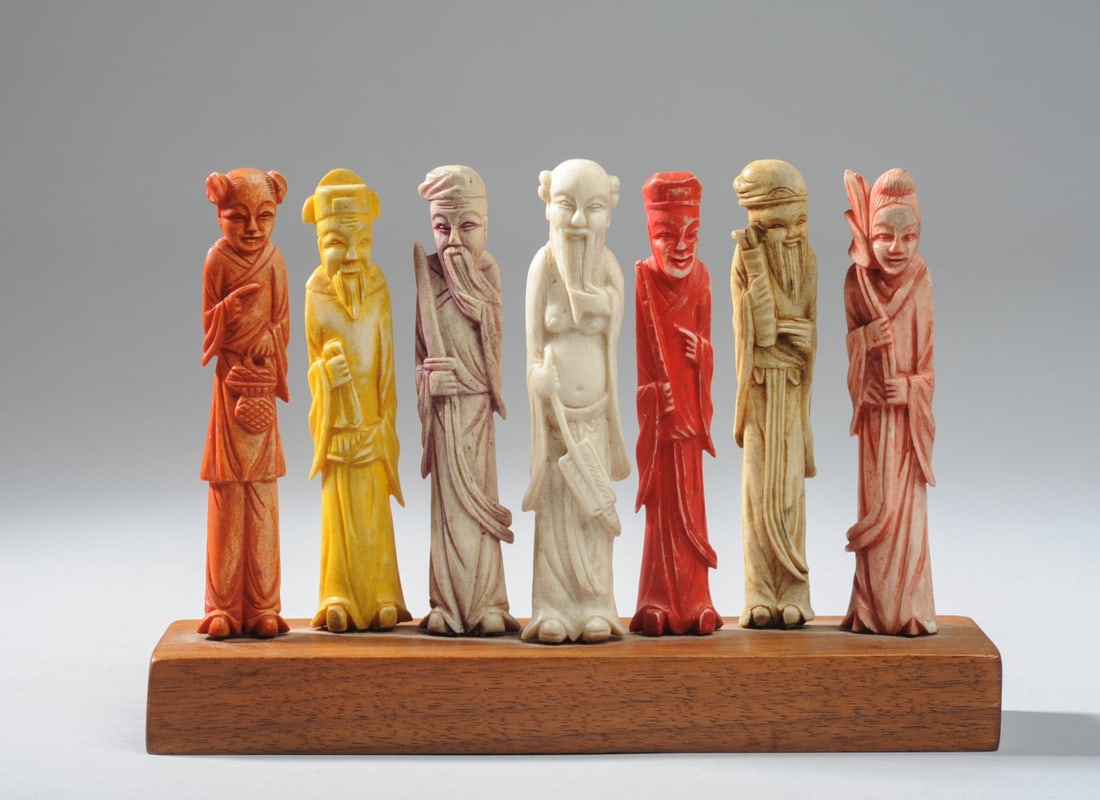 Set of Chinese Carved Bone Figures: Seven Chinese carved bone figures, possibly originally chess pieces, or simply figures of Chinese immortals. Pigmented in red, yellow, and one with vestiges of purple. All mounted together on a single