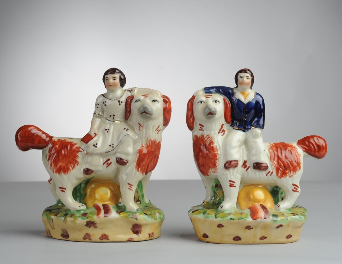 Two Staffordshire Figures, Boy & Girl on Spaniel: Charming Staffordshire pottery figures depicting a boy and girl seated on large spaniel, no visible chips, cracks or repairs. H: approx. 6 1/8". L: approx. 5". D: approx. 2 1/2". Seamless shipping is 