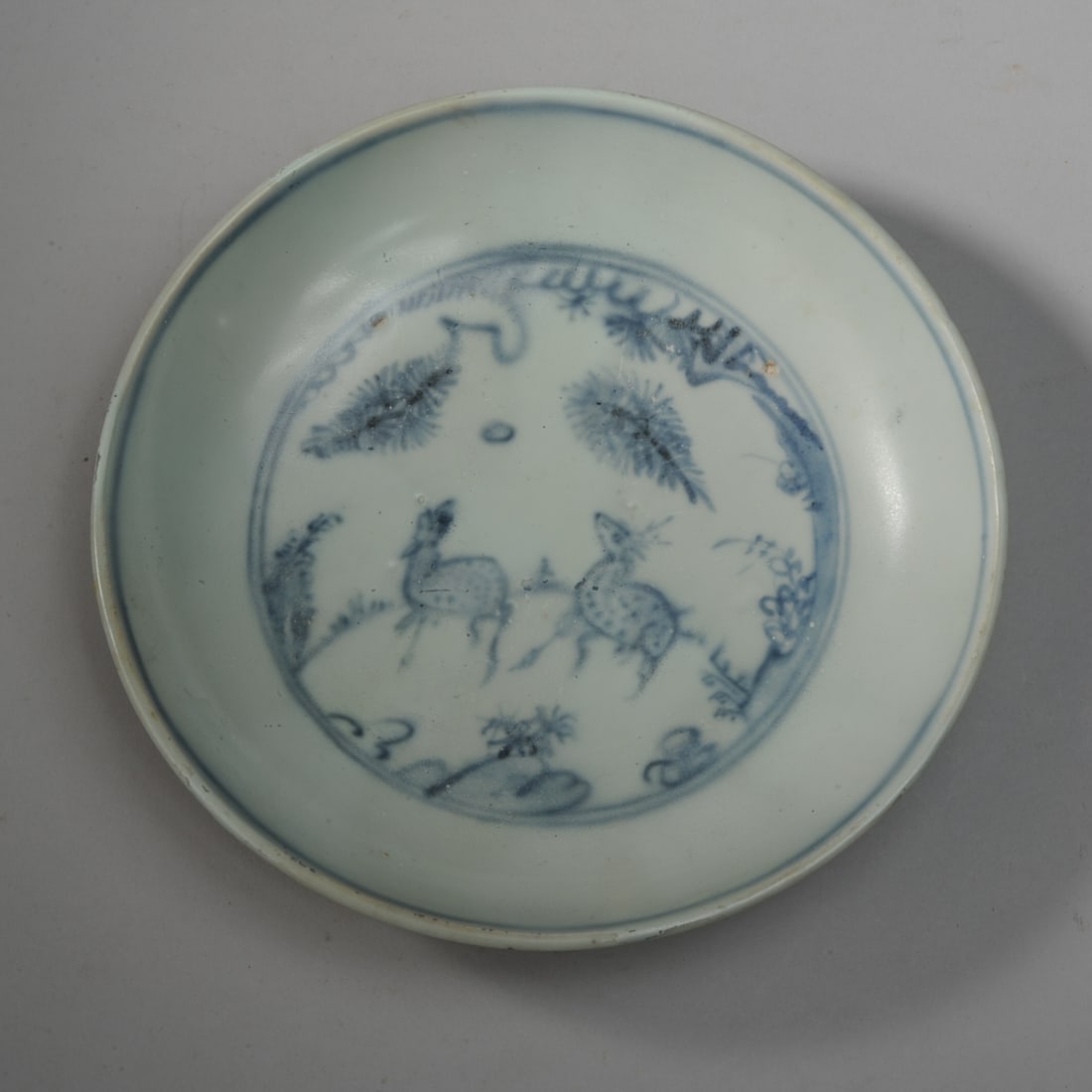 Chinese Ming / Qing Blue & White Dish: Late Ming or early Qing blue and white dish decorated with a pair of deer among fir trees in underglaze blue within a double circle. Underside with wispy lotus scrolls. Soft, soapy appearance to surfa