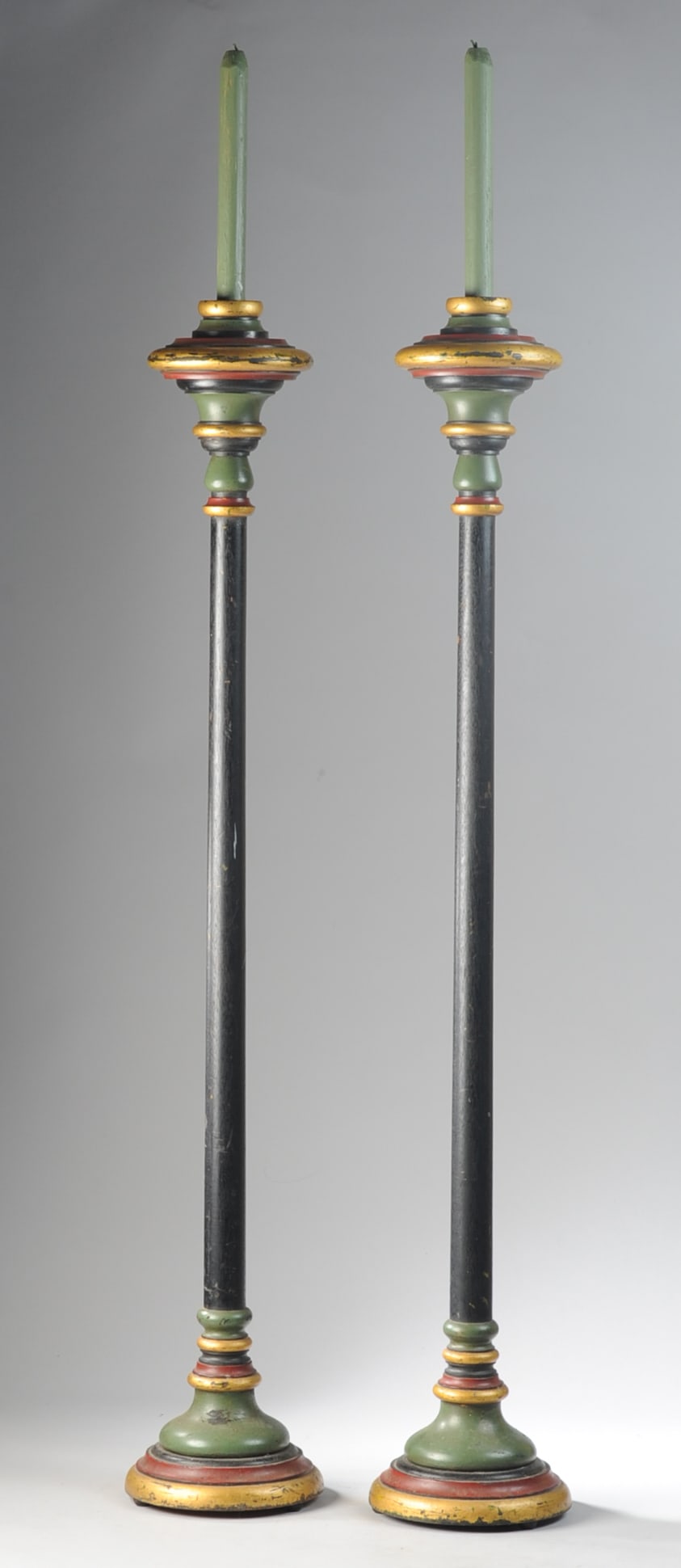 Pair of Monumental Painted Wooden Torcheres: With domed circular bases and ring turned shafts, finished in green, red, black, and gilt paint, each topped by a painted wooden “candle” finial. Minor wear. H: approx. 48". Dia: approx. 8". S