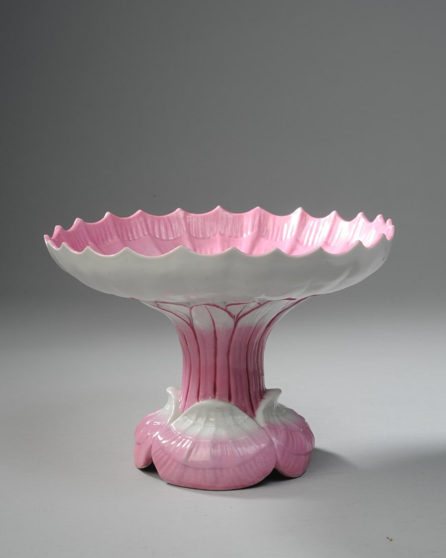 Porcelain Shell and Lotus Tazza / Pedestal Dish: Vintage or antique shell and lotus motif porcelain tazza with hand painted pink accents. Unmarked. Approx. 9" D x 6" H. Seamless shipping is available through LiveAuctioneers at checkout, but you are