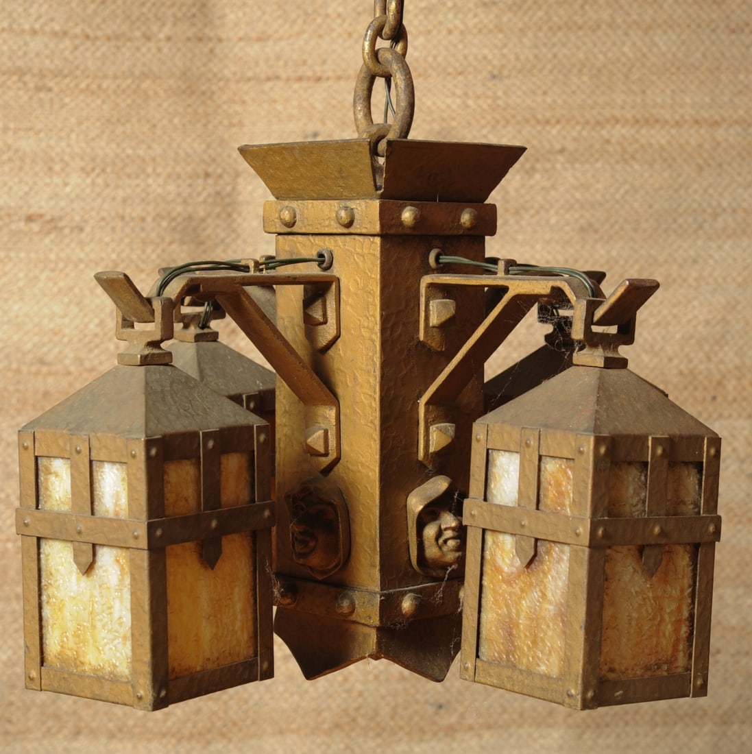 Arts & Crafts Period "Monks" Chandelier: Early 20th C. Arts & Crafts chandelier in wrought iron and steel with hammered surface and old bronze / brass finish, the four square lanterns with caramel slag glass panes, the central element with f