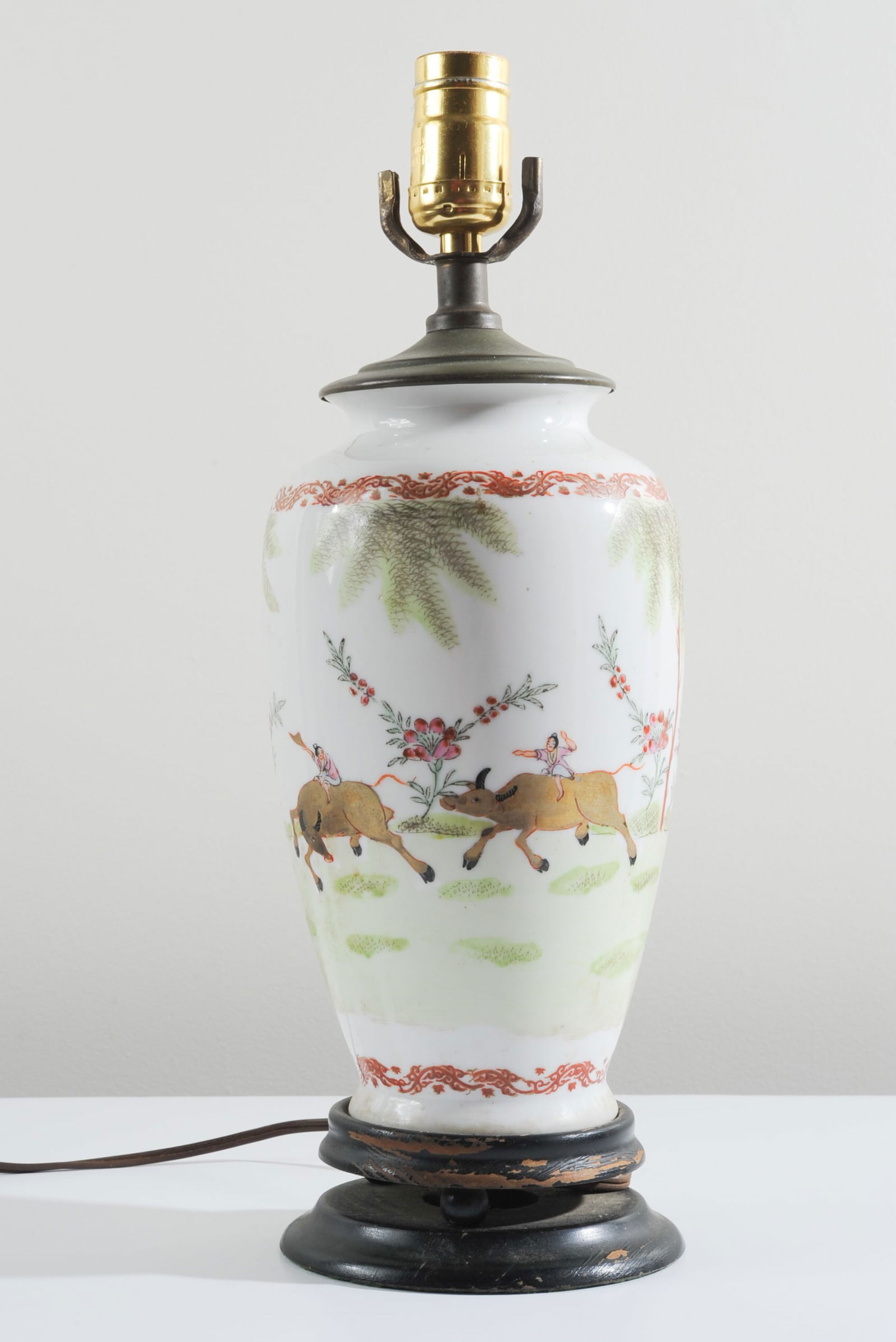 Asian Porcelain Vase as Lamp: Porcelain vase decorated with figures riding gold buffaloes in a landscape with pink flowers. Carved wood base. Plug cut off wire. Approx. 16" H to top of socket. Our primary recommendation is to arra