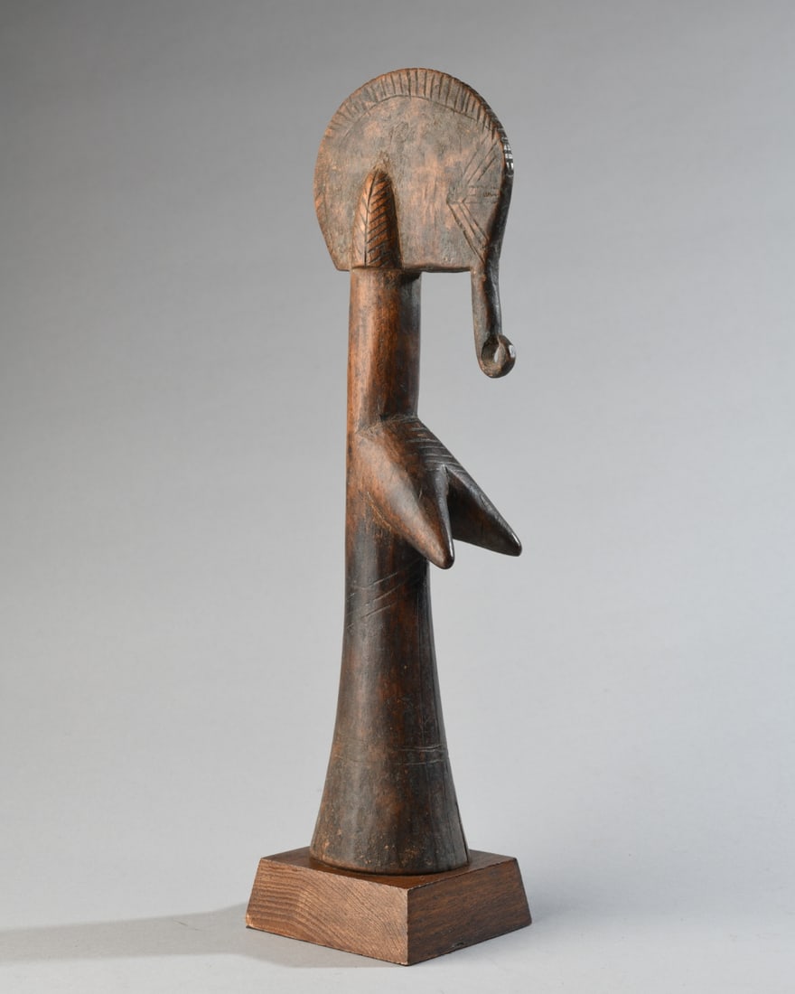 Mossi Biiga Doll, Burkina Faso: Mossi Biiga "Rad Kamba" carved wood doll of highly abstract female form. The head is flattened, with incised lines to indicate features and with a long form, curled at the end, hanging down at the