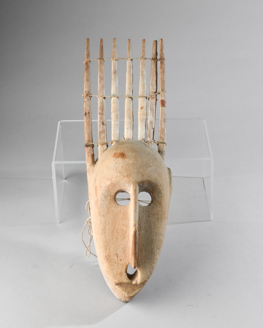 Bambara N'tomo (N'domo) Mask, Ex Michael Oliver: Southern type N'tomo mask carved of dense, light colored wood, with seven tall, vertical horns rising above the elongated anthropomorphic face, with large eye sockets, long narrow nose, and minimal