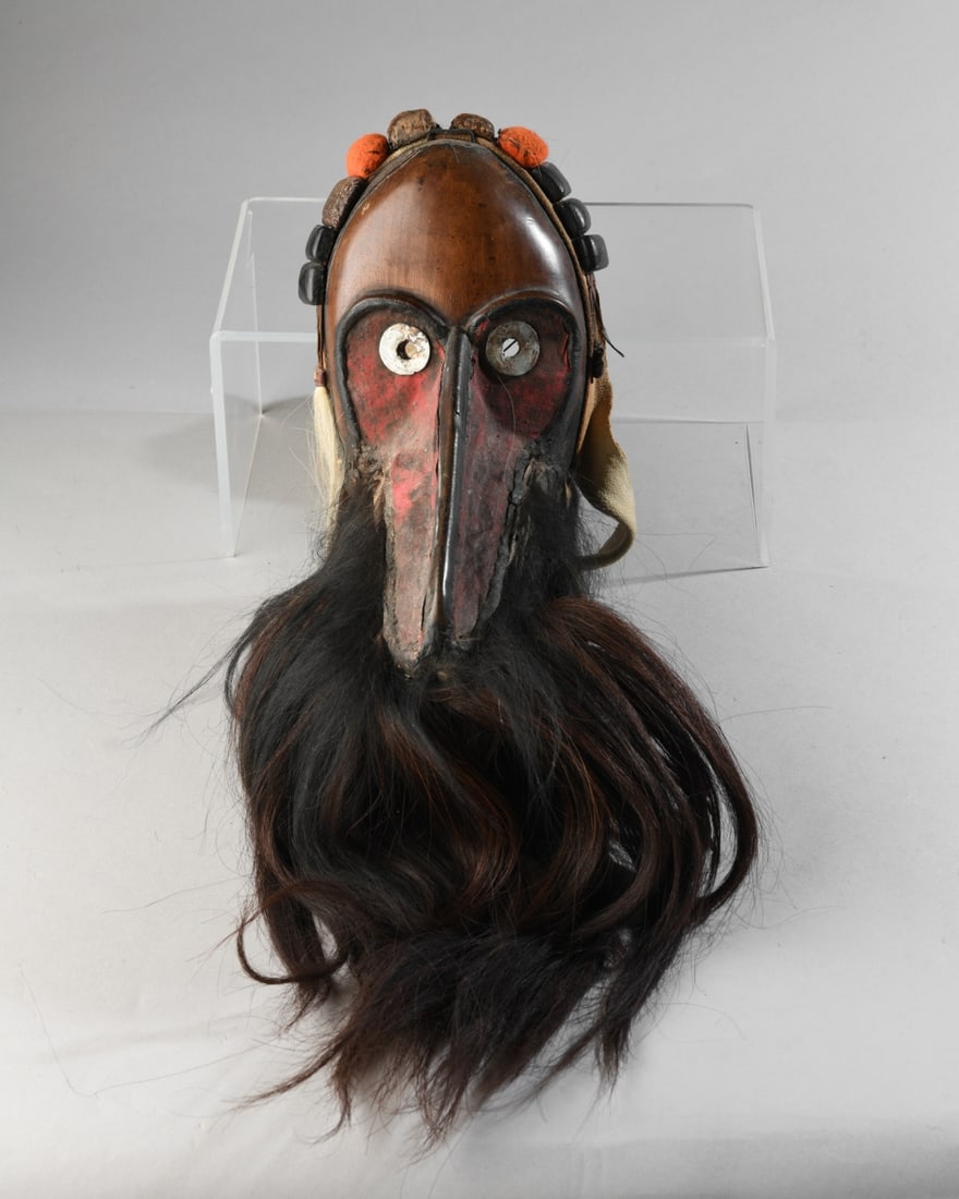 Dan Guerze Gagon Mask, ex Michael Oliver: Carved hardwood mask, the elongated nose or snout incorporating panels of red cotton. Metal disc eyes, monkey fur beard, and ten small square gris-gris packets enclosed in leather, hide, snakeskin,