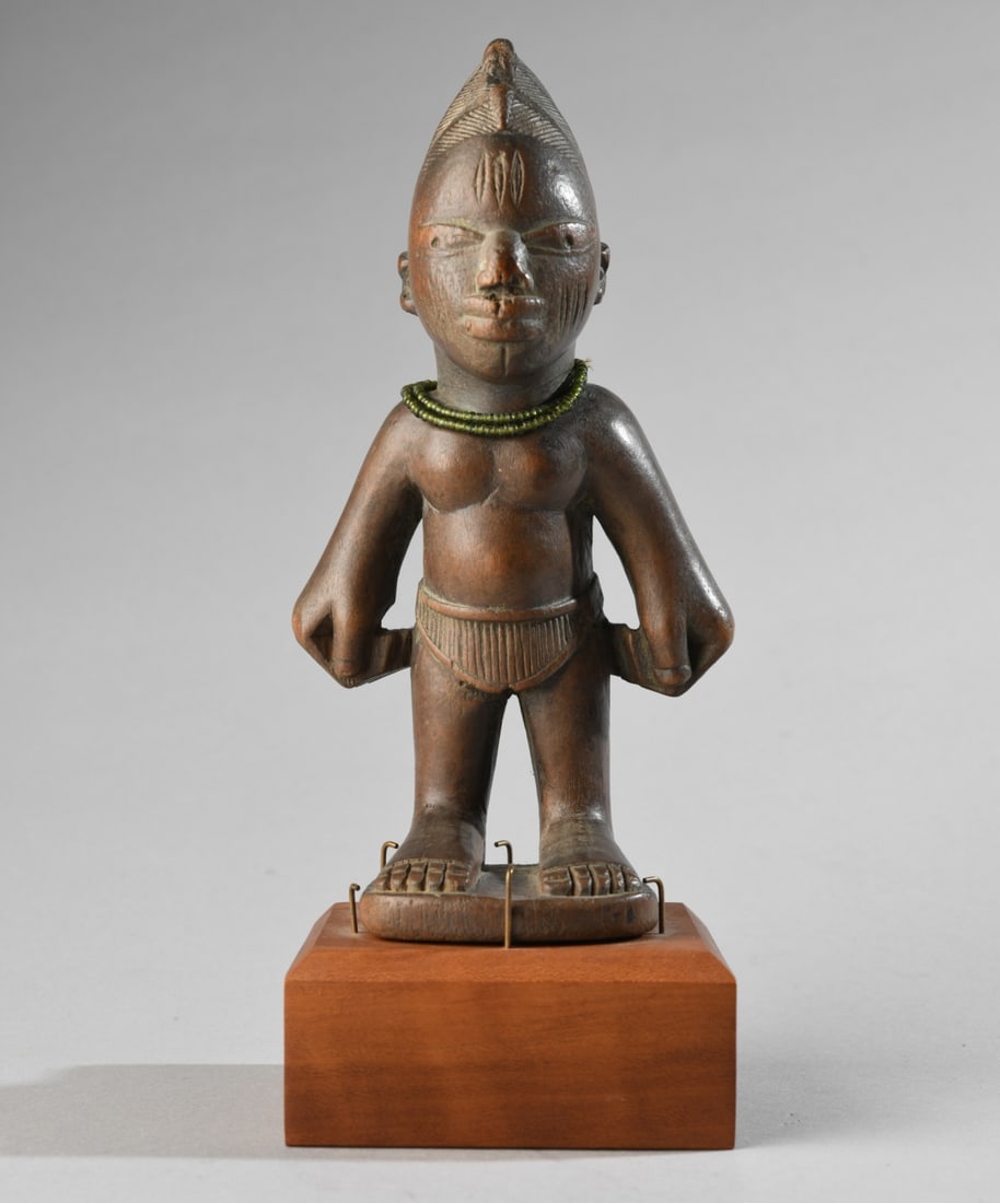Yoruba Male Ibeji Figure: Carved hardwood standing male figure with elaborate, plaited coiffure, three vertical keloid scars to forehead and cheeks, large, wide, slightly protruding eyes and full lips. The figure stands with