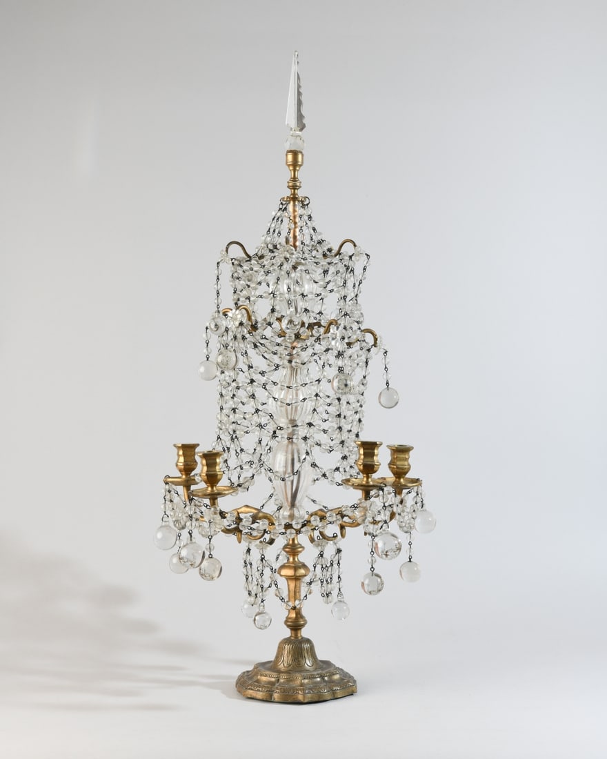19th C. Girandole Candelabrum: Brass and glass girandole candelabrum, 19th century, the central standard issuing four candle arms and hung with faceted glass bead swags and pendants, surmounted by a glass finial. Dimensions approx.