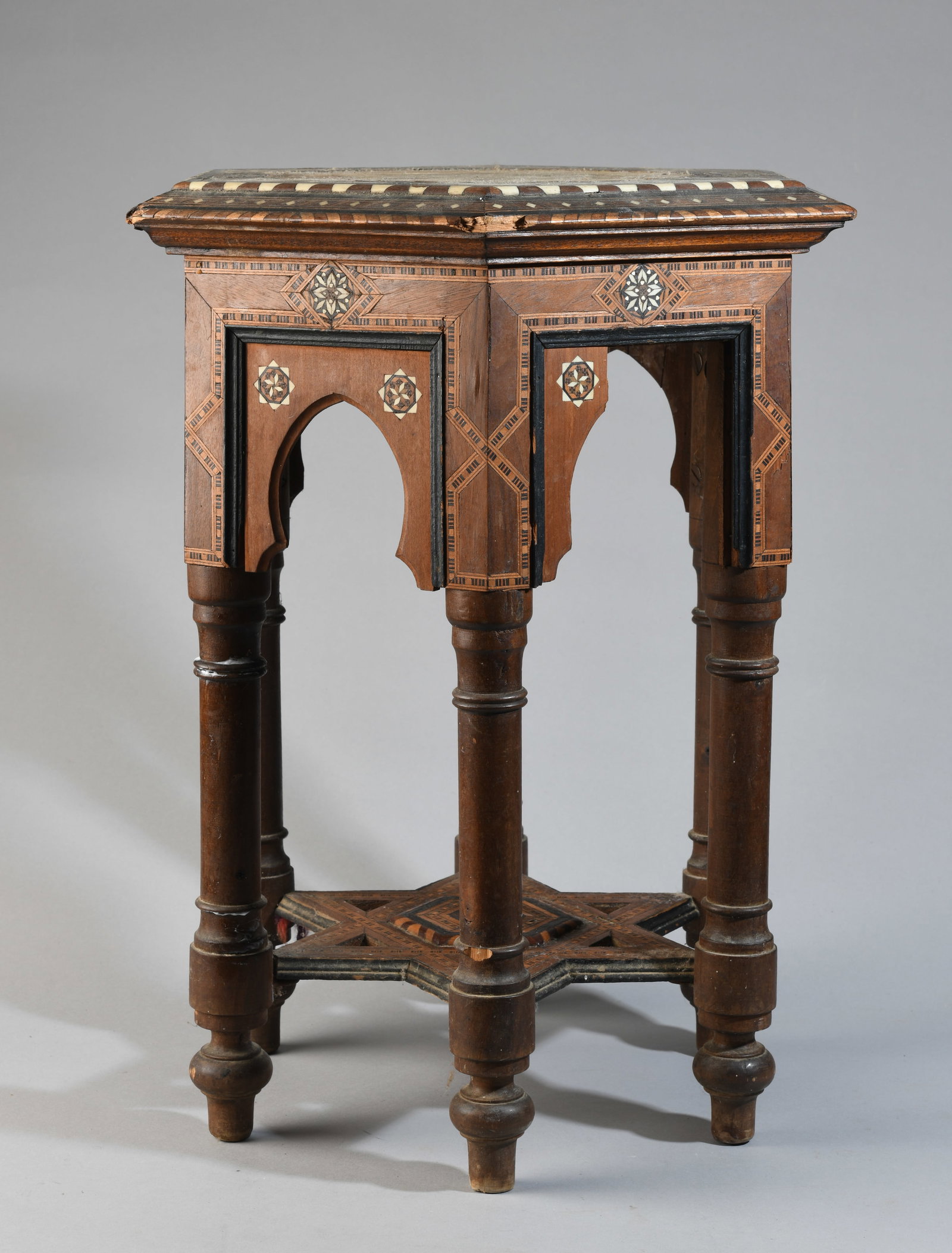 Islamic Revival Style Inlaid Occasional Table: Octagonal top with geometric inlay and calligraphic-style reserves, on a multi-arched frieze, raised on turned legs joined by a star-form stretcher; late 19th / early 20th century. Significant wear