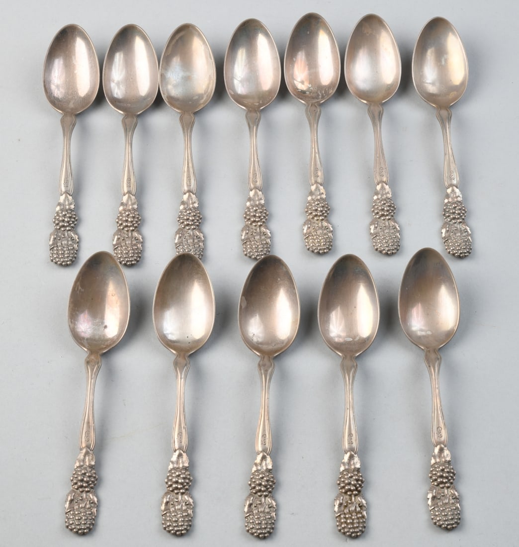 12 Tiffany & Co. Sterling Silver Spoons: In the Blackberry pattern, all monogrammed, with Tiffany cloth holder, some damage / wear to cloth. L: approx. 5 7/8". Total weight: approx. 14.66 ozt.Our primary recommendation is to arrange