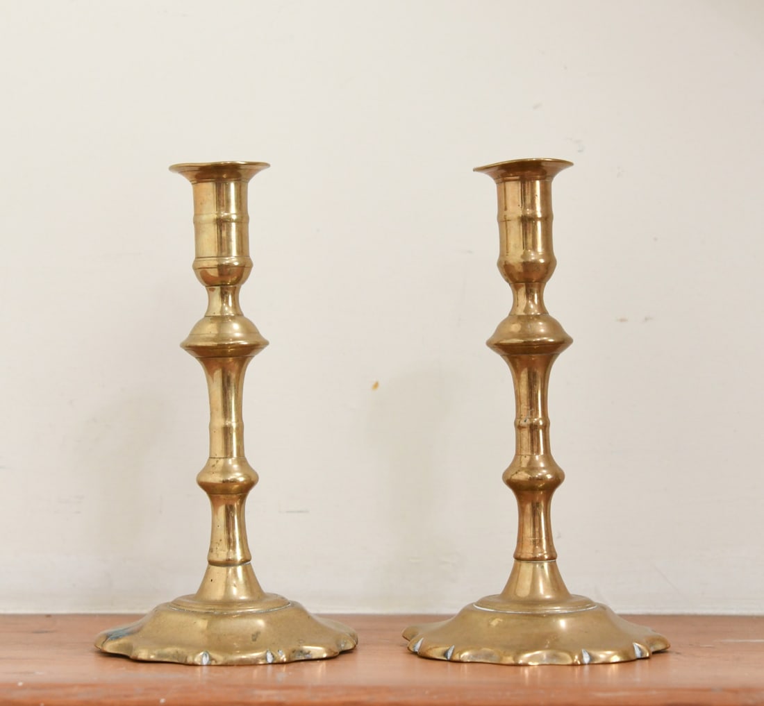 Pair of Antique English Brass Candlesticks: Each of baluster form with knopped stems and scalloped drip pans, on shaped bases; likely 19th century; minor surface wear and oxidation.Our primary recommendation is to arrange shipping yourself