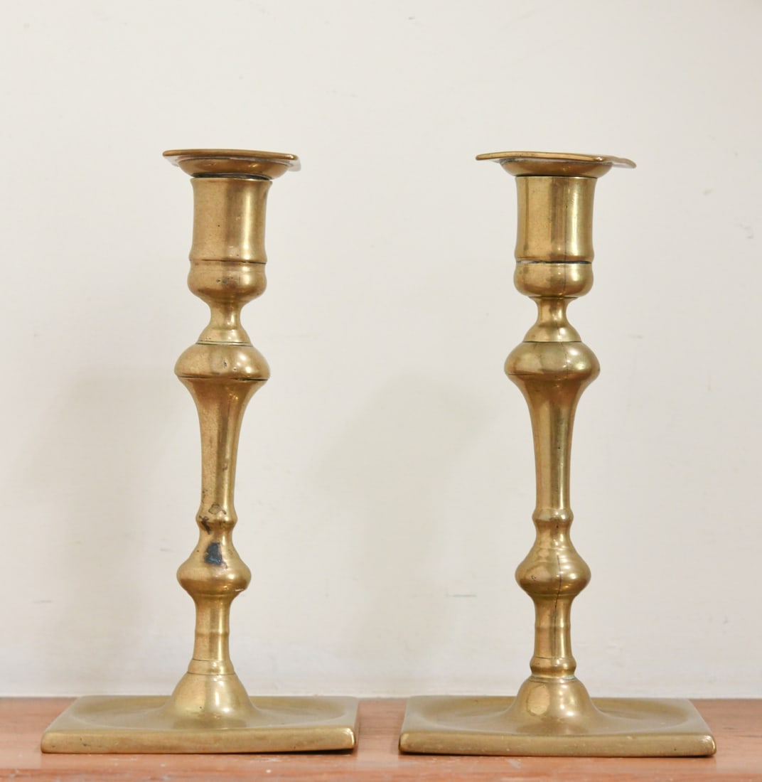 L 18th / E 19th Pr English Brass Candlesticks: Each with square ejector tops above baluster stems, on dished circular platforms and square bases; likely late 18th to early 19th century; removable nozzles; surfaces with some polishing wear and