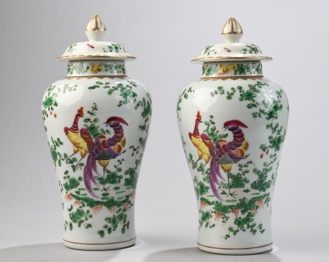 Pair of Samson Porcelain Covered Jars: A matched pair of baluster-form porcelain covered jars, each with domed lids and pointed finials. Decorated in the famille verte palette with vibrant polychrome enamels depicting exotic birds among fl