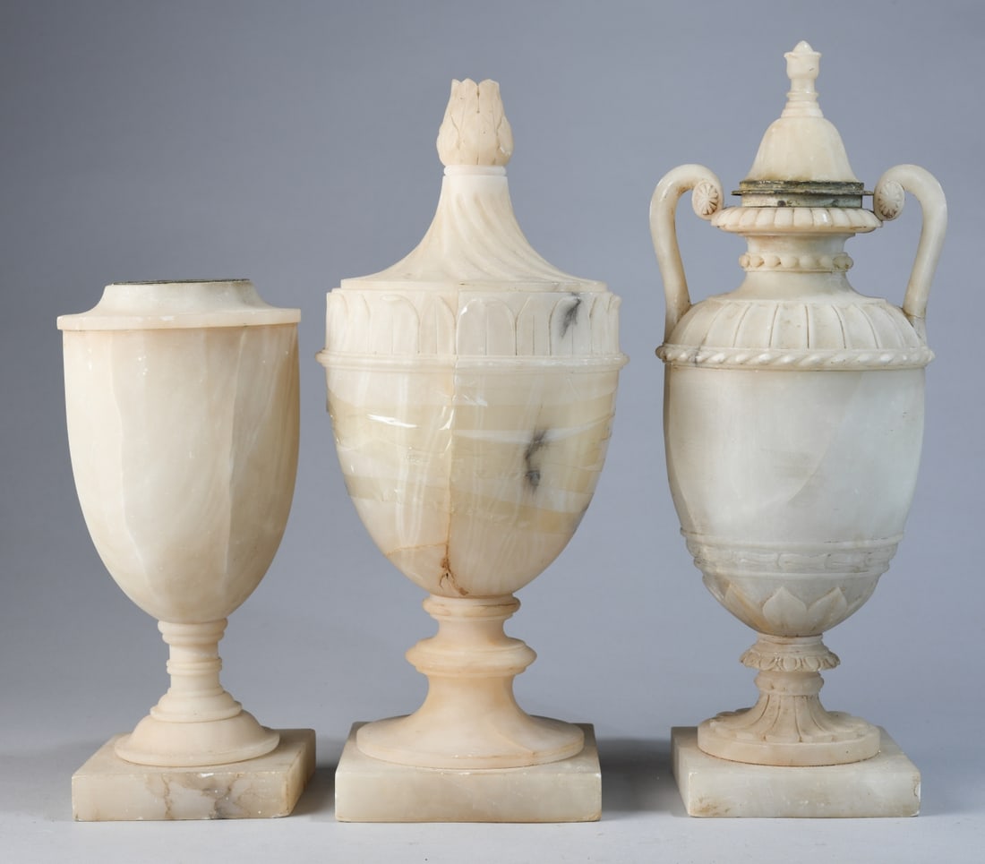 3 Carved Alabaster Urns: Likely late 19th to early 20th century, comprising three urn-form vessels including two with covers, and one open urn with flared rim, all raised on square bases; varying carved decoration including f