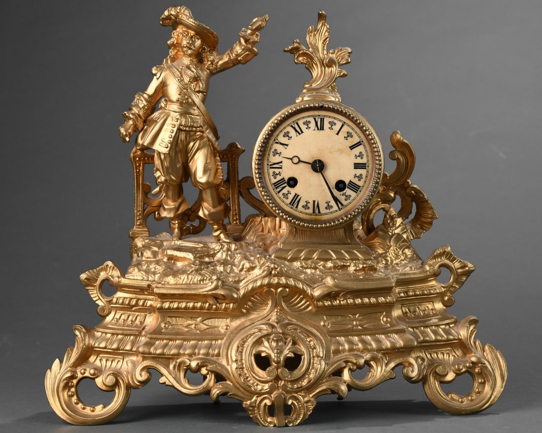 Figural Musketeer Mantel Clock: Figural mantel clock, gilt spelter, French style, with musketeer beside a drum-form case on a Rococo base; Roman dial with twin wind holes, bell strike movement, 20th century, untested / in as-found c