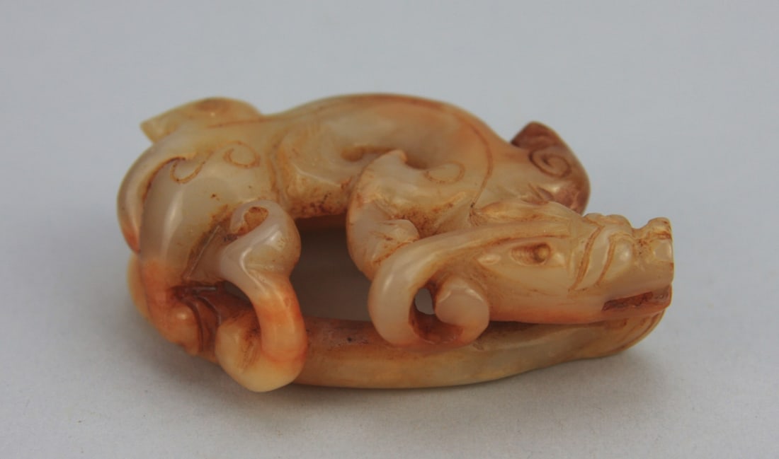 Chinese Carved Figure of a Dragon: Chinese carved celadon, white and russet figure of a coiled dragon. Light surface wear. 3 1/4" long 2 1/4" wide. Our primary recommendation is to arrange shipping yourself using Blue Ridge Pack & Ship