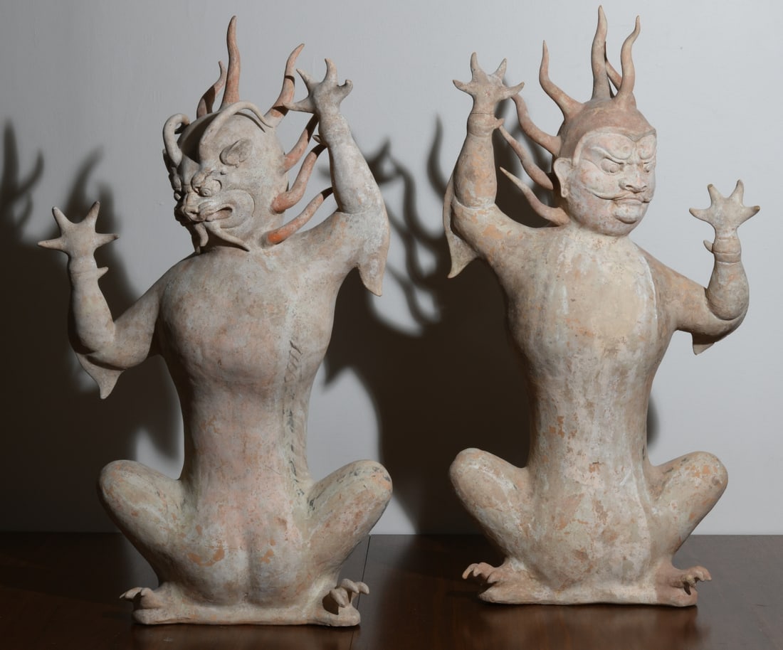Pair Chinese Tang Dynasty Pottery Earth Spirits: Pair of Chinese painted pottery earth spirits (zhenmushou), Tang Dynasty (618–907 AD), each modeled in a squatting posture with fierce zoomorphic face, bulging eyes, and snarling fanged mouth, the h