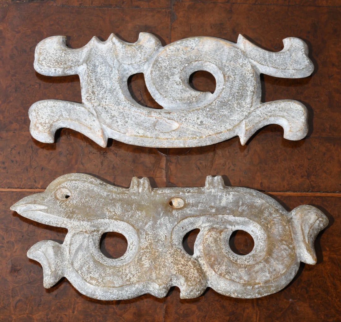 Pair of Chinese Hardstone Carvings: Possibly jade or jadeite, each of stylized archaistic zoomorphic form with scrolling bodies and circular apertures, surfaces with mottled gray-green tone, drilled apertures, minor chips. Largest appro