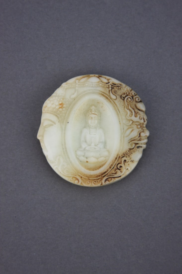 Chinese Carved White Jade Circular Pendant: Chinese carved white jade circular pendant depicting kwan yin in the center, a calligraphy character on the obverse and two demon heads on the sides. Light soiling as seen in the photos. 2" diameter. 
