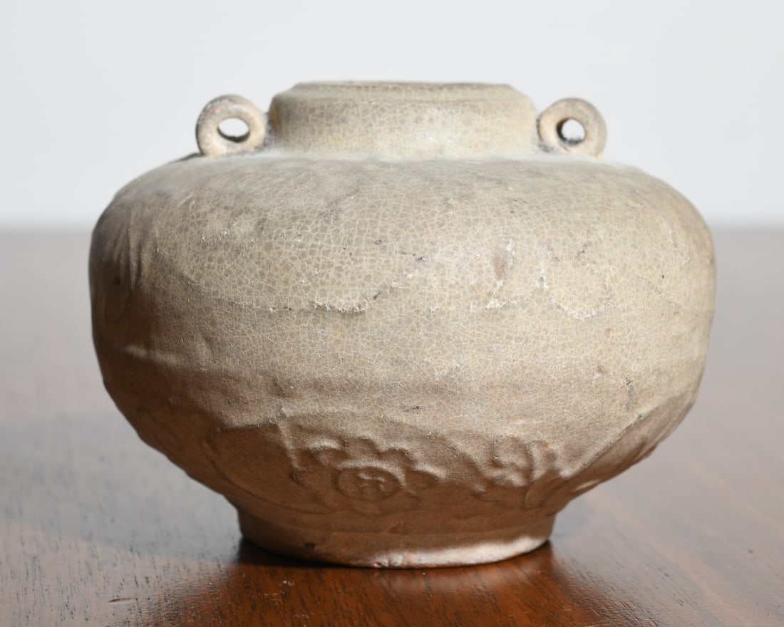 Chinese Archaistic Pottery Jar with Lug Handles: Compressed globular body rising to a short cylindrical neck, flanked by a pair of small pierced lug handles, the surface with molded and incised decoration. Raised on a short foot with exposed terraco