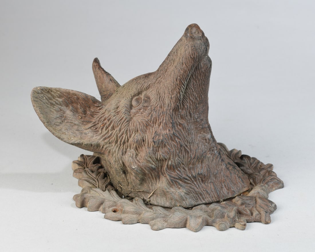 Cast Metal Fox Head Wall Mount: Cast iron wall mount modeled as a fox’s head, emerging from a stylized foliate surround, naturalistically detailed with textured fur and open back Some rust. Dimensions approx. 12" x 9 1/2" x 8 1/2"