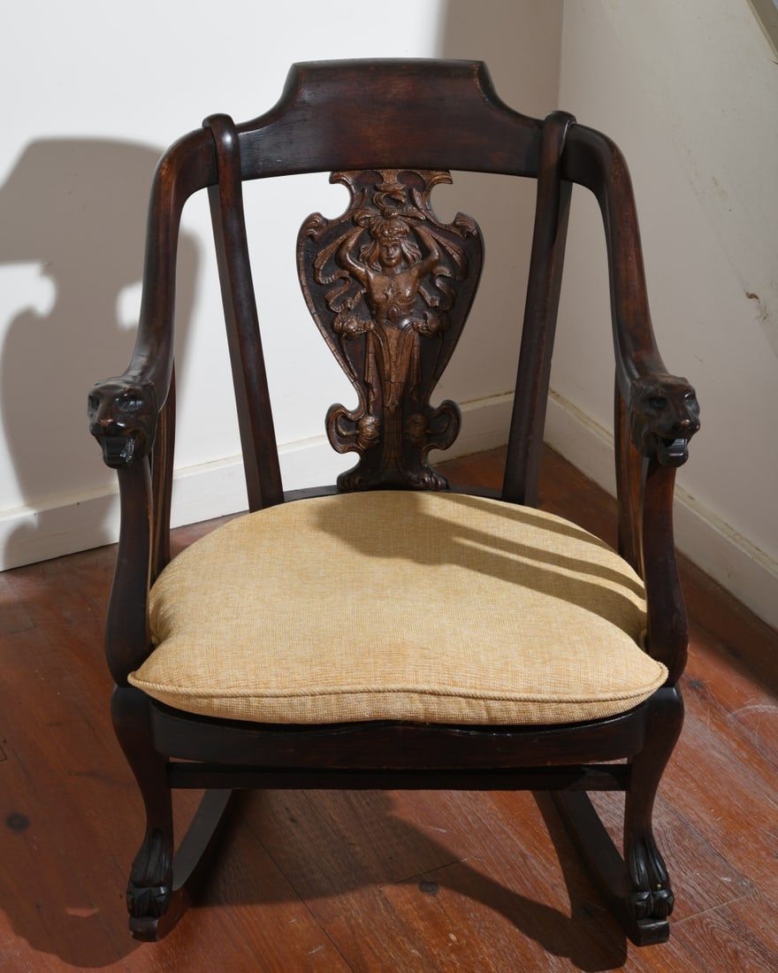 Aesthetic Movement Rocker: Carved mahogany rocking chair, probably American or Continental, late 19th/early 20th century. The crest rail above a carved female figural splat, the scrolling arms terminating in carved animal heads