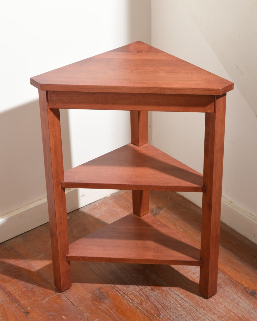 Contemporary Corner Table: Cherry-finished wood construction, probably late 20th / early 21st century, with triangular top above two triangular shelves on square legs. Clean modern design suitable as a lamp or occasional table.