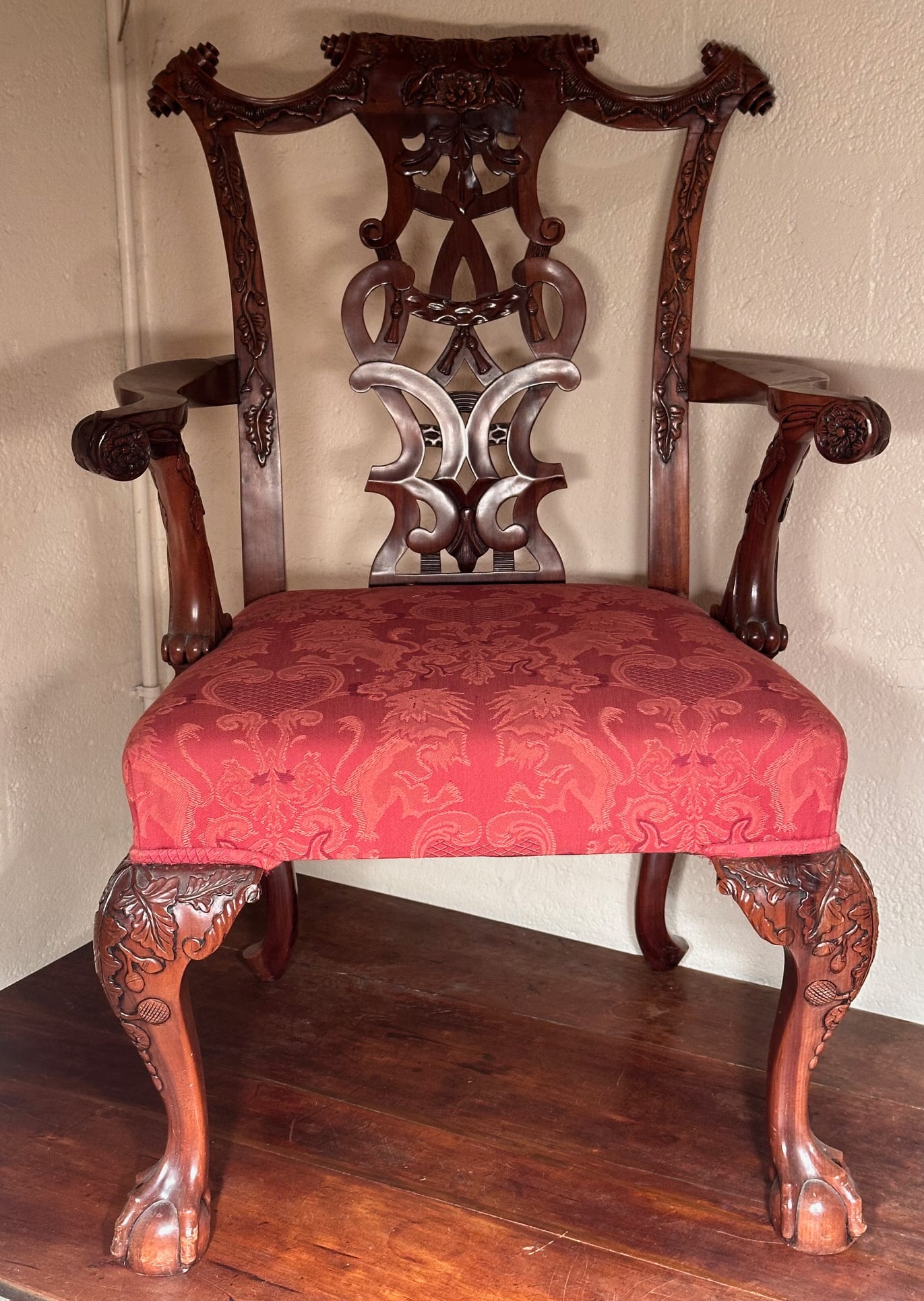 Carved Mahogany Chippendale Style Arm Chair: Shaped crest above a pierced splat flanked by scrolling open arms, with upholstered seat, raised on carved cabriole legs terminating in ball and claw feet. 20th century. H: approx. 39 1/2". W: approx.