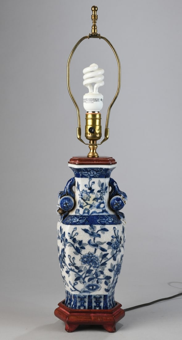 Chinese Blue and White Lamp: Ceramic body of baluster form with crackle glaze decoration, painted with flowering vines and birds, with applied molded mask and ring handles and floral motifs, mounted to wood base. Powers on. Dimen
