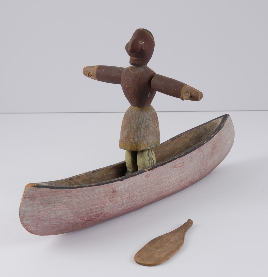Antique Folk Art Figure, Indian in Canoe: Late 19th / early 20th C. American or Canadian carved and painted wood figure, likely a whirligig, showing a Native American standing in a canoe, arms outstretched. Paddles were originally attached to